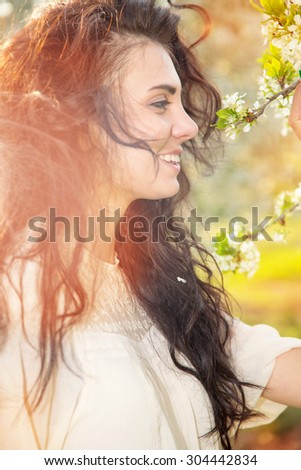 Portrait beautiful brunette woman in sunset light. Woman on nature background summer / spring. Enjoying the nature. Young woman arms raised enjoying the fresh air. Fashion woman model. Beautiful smile