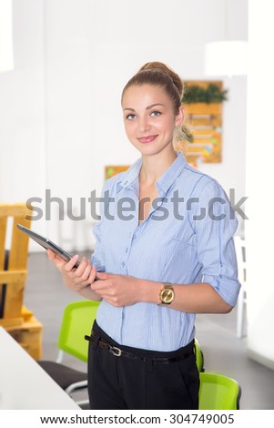 Portrait beautiful woman on the background of modern business office. Modern businesswoman holding tablet computer on background office space.
