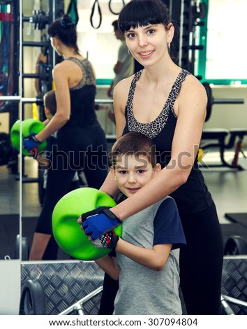 Sport children and parents. Woman mother with boy in fitness club. Joint exercise sports with the child. Client fitness center. Mother and son while standing close to each other in gym. Family fitness