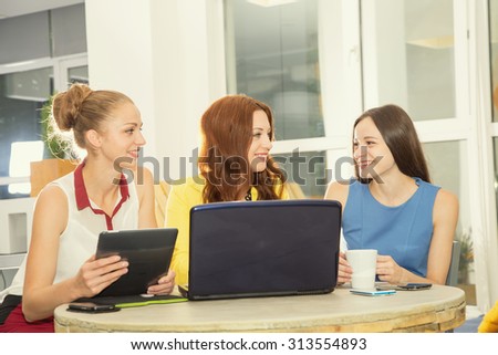Three women - students, young women office workers. Meeting, to discuss joint issues. Teamwork on the project. Multinational team of female indoors office or conference room for training. Toned image