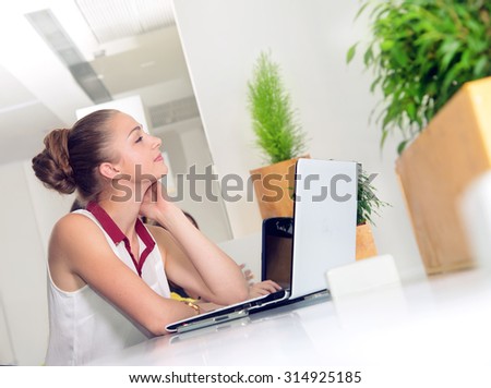 Woman dreaming about vacation or about new purchases. Woman dreams. Woman with laptop. Young woman working at a laptop in the office. Business woman, office worker. Girl student to work at a computer.