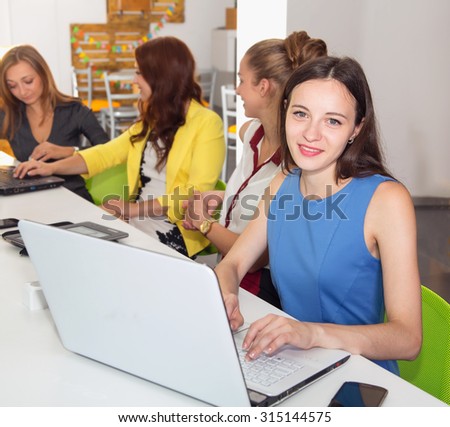 Attractive girl university student using laptop in classroom. Female college students using laptop at desk in computer class. Woman student with laptop working in a university library.