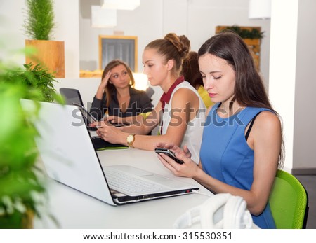Attractive girl university student using laptop in classroom. Female college students using laptop at desk in computer class. Woman student with laptop working in a university library.