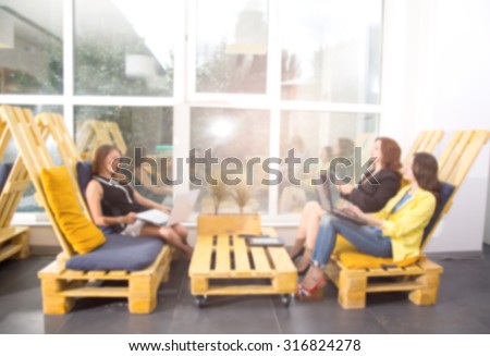 Blurred image. Blurred people. Working day. Office life. Meeting. Work in the women\'s team. Group young women - office staff. Discussion of the project. Women students. Blur background image.