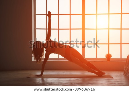 Silhouette fitness woman. Woman silhouette in the window sunset background. Space for text.