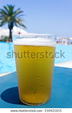 A glass of cold beer in front of the pool