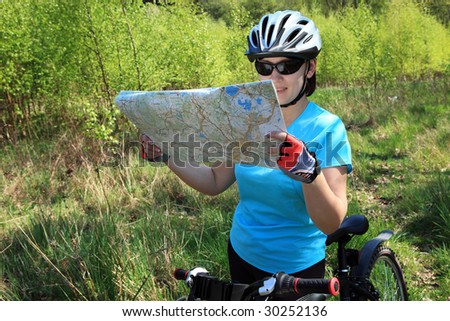 Summer theme. Woman on bicycle reading a map.
