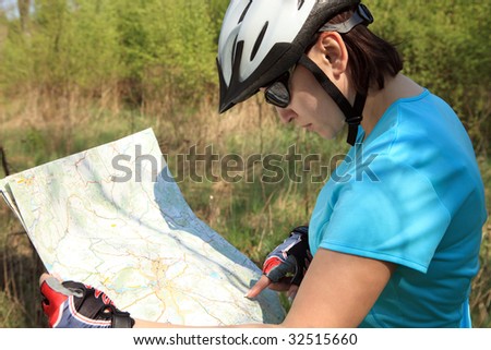 Summer theme. Woman on bicycle reading a map.