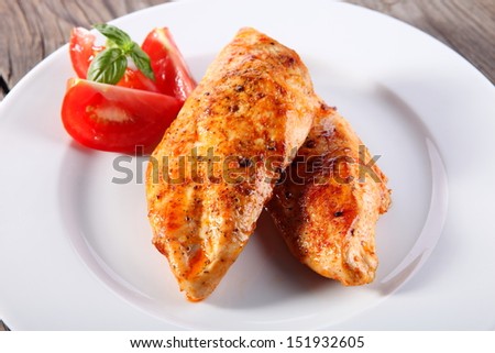 Grilled organic chicken with tomato on wood