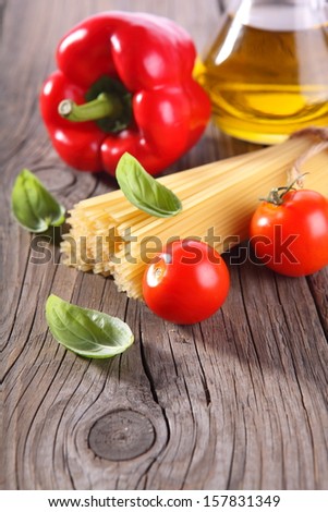 Spaghetti and tomatoes with herbs on an old and vintage wooden table