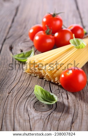 Spaghetti and tomatoes with herbs on an old and vintage wooden table Spaghetti