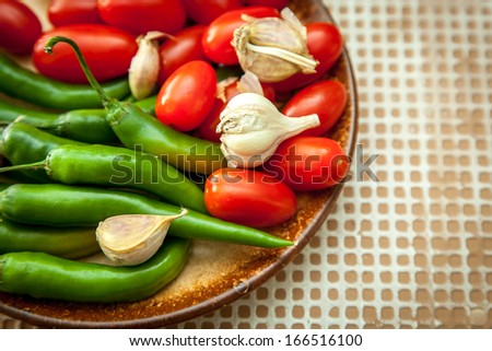 chilli peppers, cherry tomatoes and garlic on a brown plate