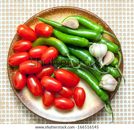 chilli peppers, cherry tomatoes and garlic on a brown plate