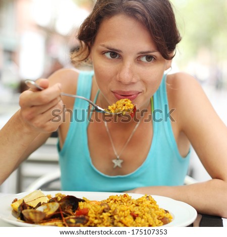 young woman eating spanish paella in a cafe young woman eating spanish paella in a cafe