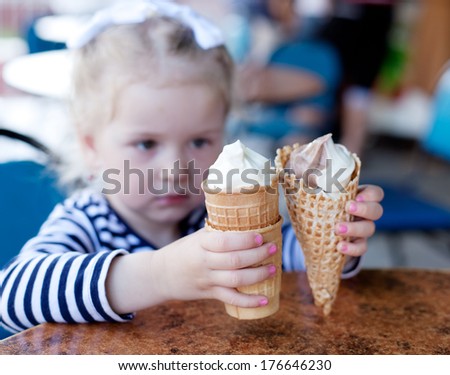 little girl, 3 years old, with blond hair eating ice cream in a cafe
