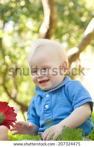 funny little boy sitting on the grass in the park