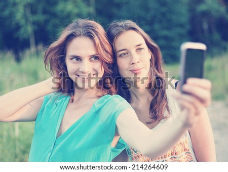 two beautiful girls make selfie on a mobile phone