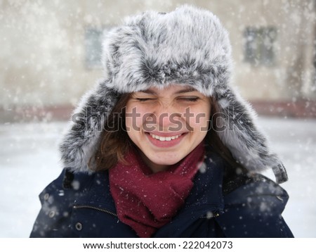 cute funny happy  girl in a fur cap  laughing under the snow