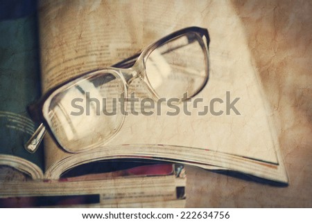 glasses for reading on a stack of magazines. With the effect of crumpled paper