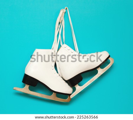 white ice skates for figure skating, hanging on a blue background