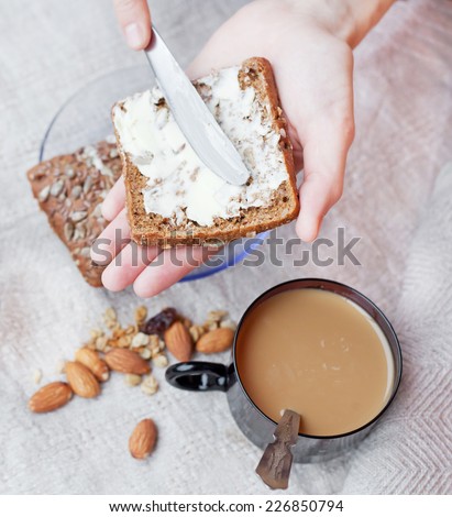 woman hand  rubs butter on piece of rye bread, with selective soft focus