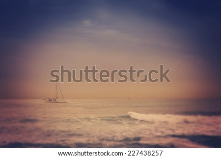 blurred retro image of small yacht in the sea, with tilt shift effect and retro toning