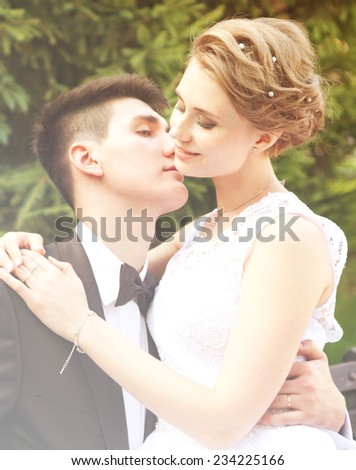 gently groom kisses the bride, wedding day, image with soft focus with sunshine glares