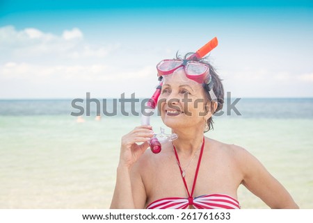 older woman with a mask for snorkeling in the sea background