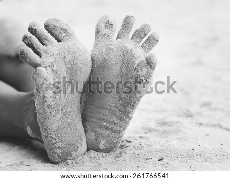 funny woman's feet on the white sand near the sea. Concept black and white