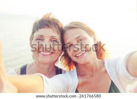 mother and adult daughter are doing Selfe on the beach
