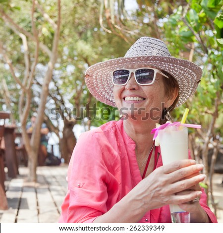 beautiful elderly woman in a hat with a cocktail in hand. Summer, vacation, holiday, active retired people