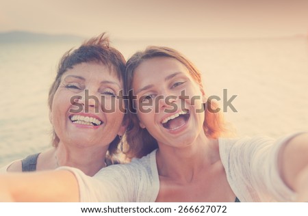 mother and adult daughter are doing Selfe on the beach