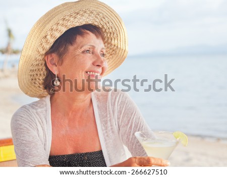 beautiful 50 years old woman in a hat with a cocktail in hand. Summer, vacation, holiday, active retired people