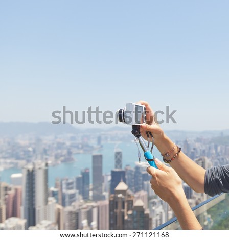 Selfie stick with the camera in the hands of the girl on the background of Hong Kong