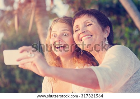 mother and adult daughter are doing Selfe on the beach. Image with retro toning