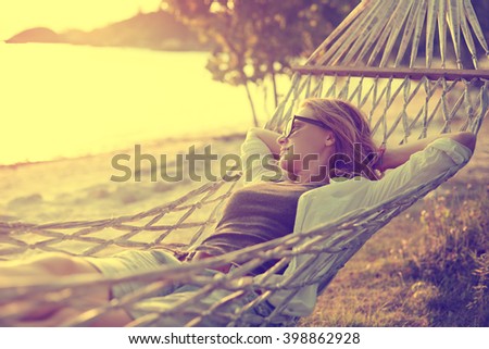 beautiful girl in a hammock on the beach, watching the sunset. Image with retro filter
