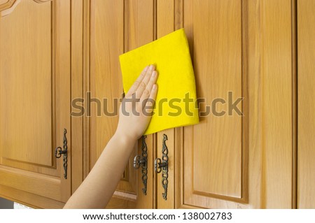 Young woman in the Kitchen doing Housework cleaning cupboards