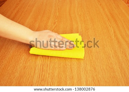 woman cleaning furniture table with yellow cloth