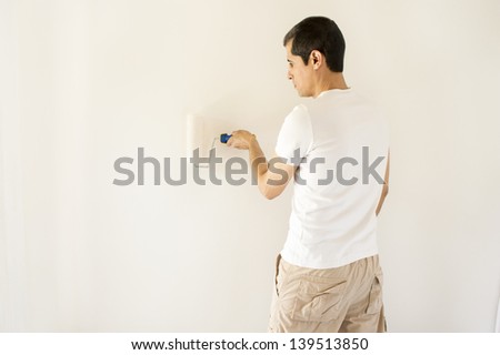 man painting white wall with roller