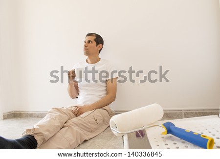 relaxed painter taking a tea sitting on the floor
