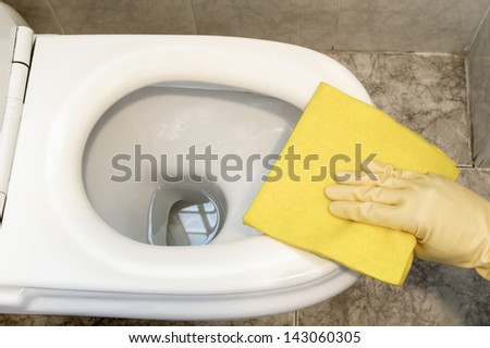 woman cleans a toilet with yellow cloth