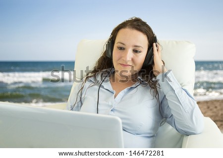 Cute women female listening to music on the laptop on the beach
