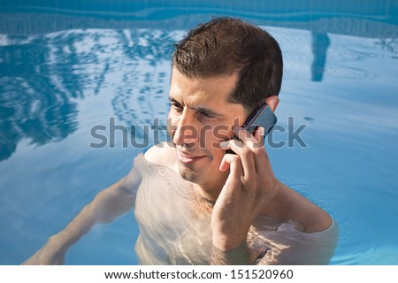 smiling businessman using phone by swimming pool