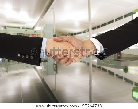 Businesswoman and businessman shaking hands in commercial office
