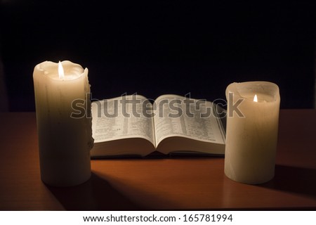 table with an open Bible with candlelight