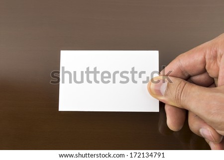 hand holding a blank placard with a wooden table background