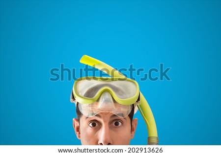 close up of man with snorkel mask looks surprised with blue background