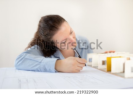 Close Up of an female architect adding to his planning next to a miniature