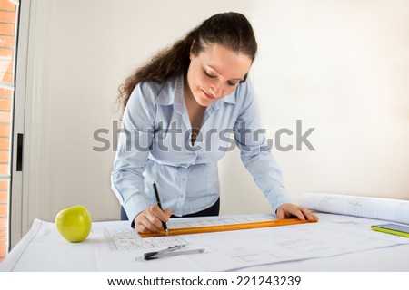 Close Up of an female architect adding to his planning next to a apple