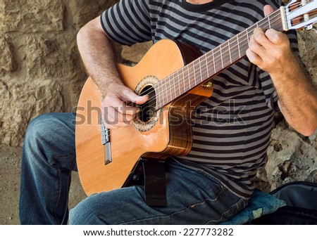 bohemian performer playing spanish guitar in a street